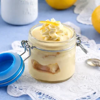 Lemon cream dessert layered in a glass jar with whipped topping and zest.