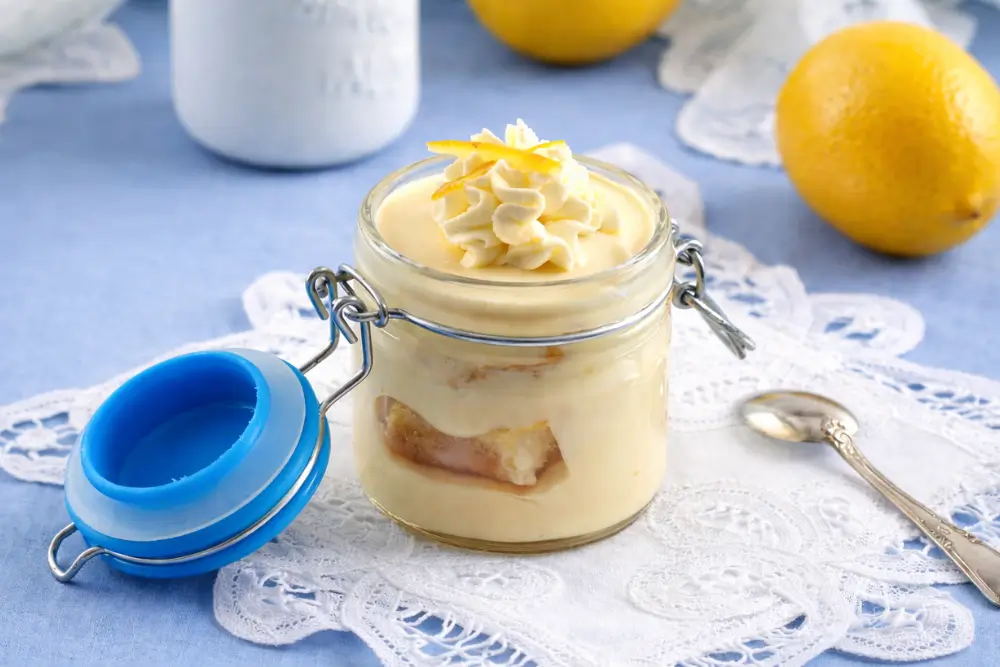 Lemon cream dessert layered in a glass jar with whipped topping and zest.