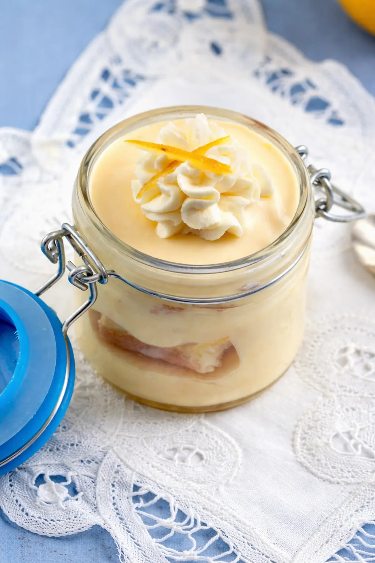 Close-up of creamy custard dessert topped with whipped cream and lemon peel.