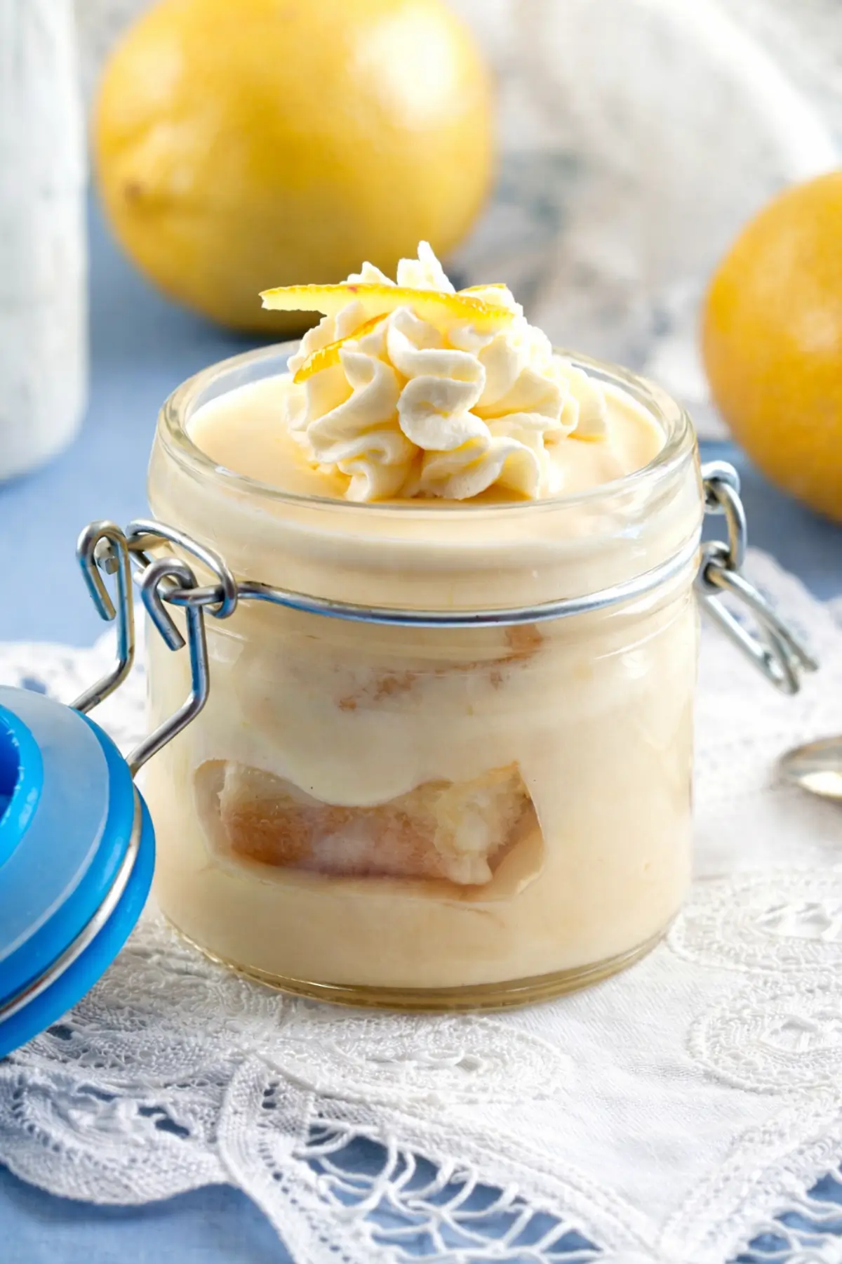 Lemon dessert in a jar topped with whipped cream and lemon zest.