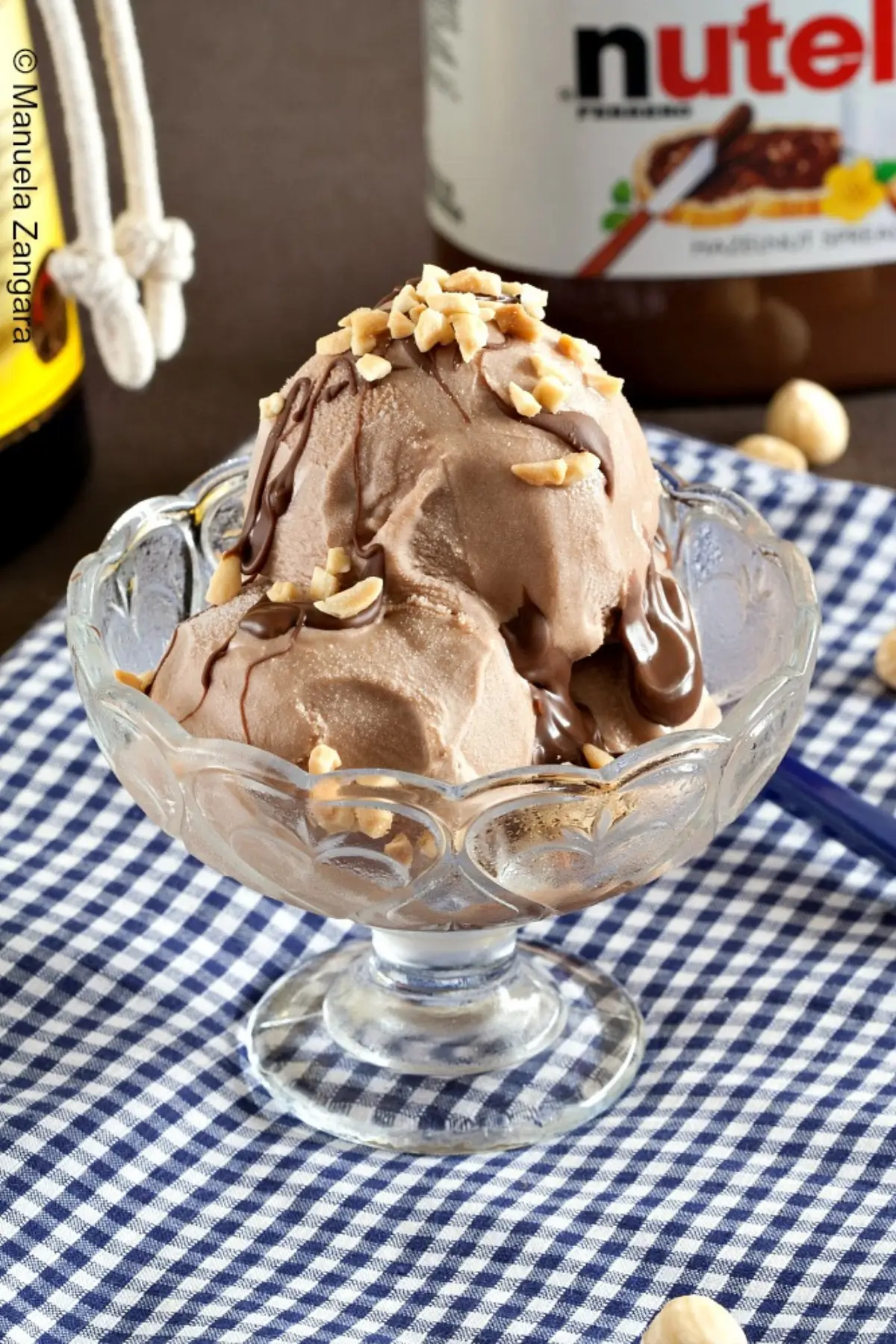 Nutella Gelato with Frangelico served in a glass bowl with warm Nutella drizzle and chopped hazelnuts.