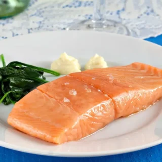 Salmon Confit served with homemade aioli on a white plate.