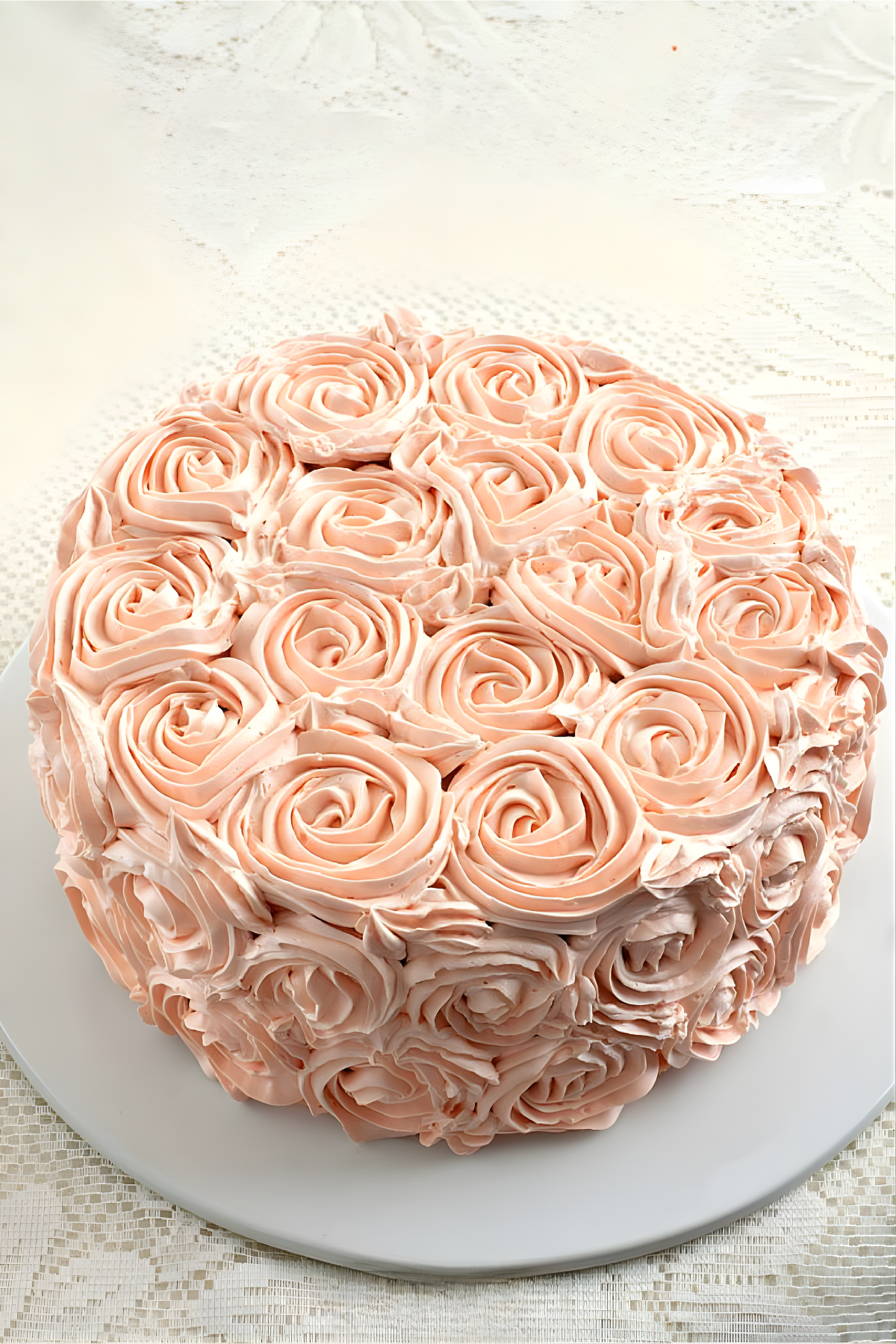 Pink rosette cake on a stand with piped buttercream roses.