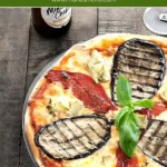 Baked Pizza Ortolana with a golden crust, grilled eggplant, roasted red peppers, and artichoke hearts, topped with fresh basil.