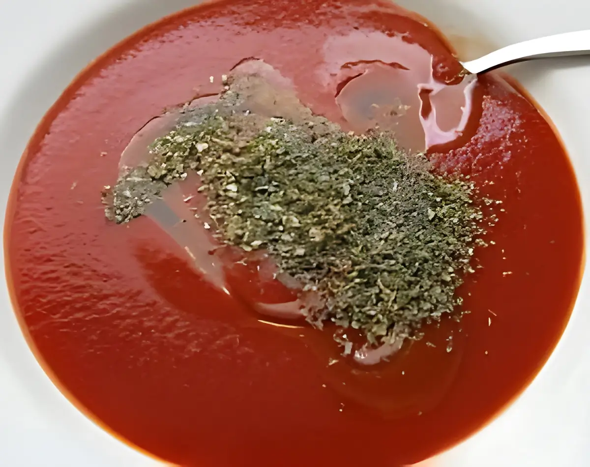A bowl of tomato purée with oregano and olive oil mixed in.