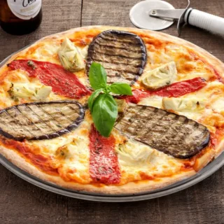 Freshly baked pizza ortolana with grilled eggplant, roasted red peppers, artichokes, and fresh basil on top.