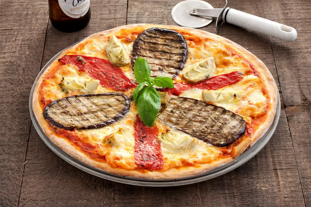 Freshly baked pizza ortolana with grilled eggplant, roasted red peppers, artichokes, and fresh basil on top.