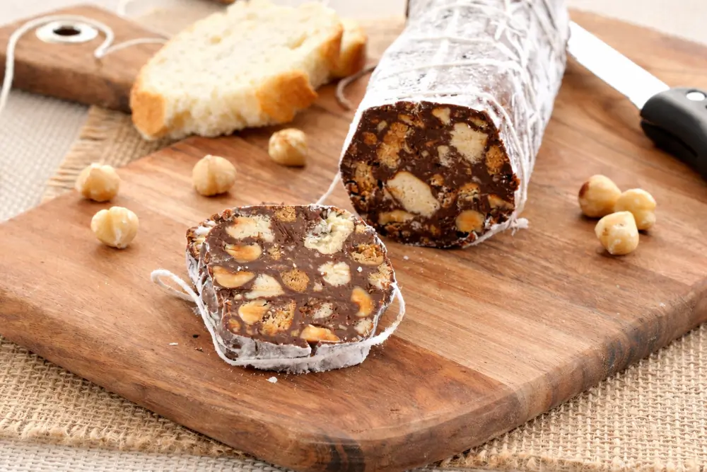 Chocolate biscuit slices served on a wooden board with hazelnuts.