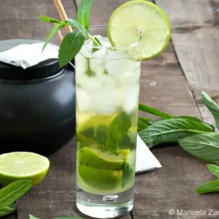 Green Tea Mojito served in a tall glass with mint leaves, lime slices, and ice.
