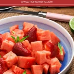 Watermelon and Strawberry Salad with Ginger and Lime Syrup served in a blue bowl with fresh mint and lime.