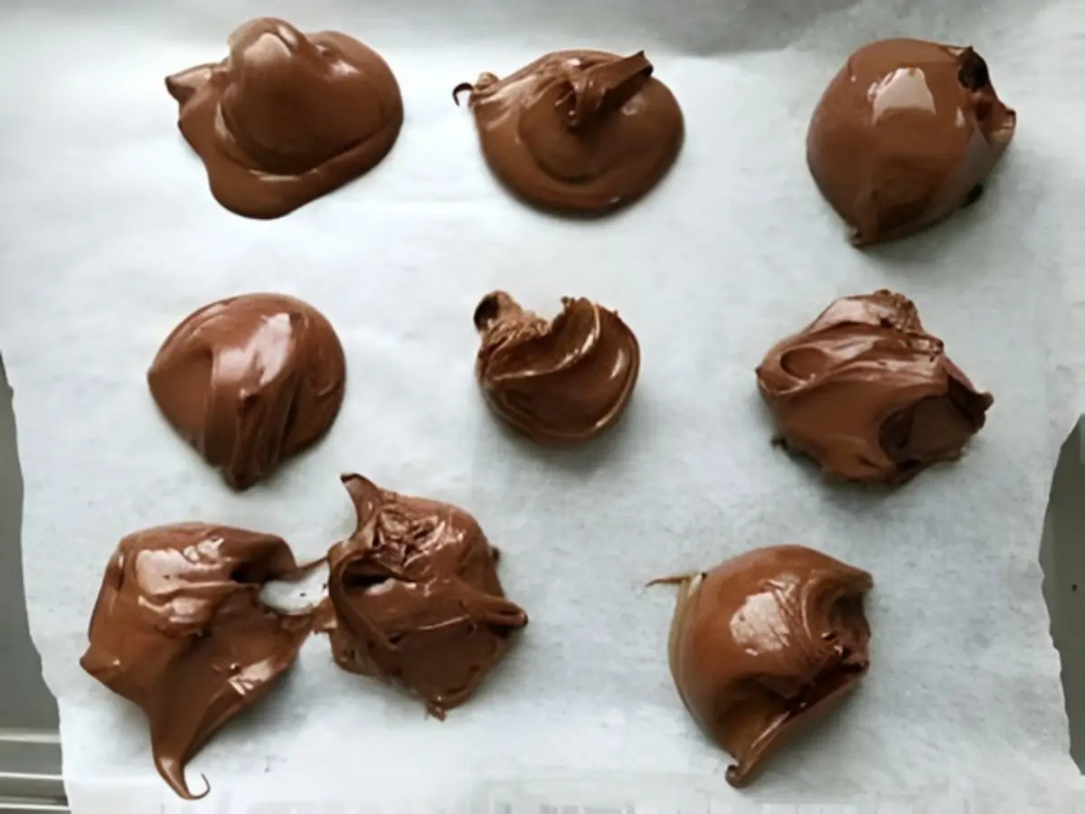 Spoonfuls of Nutella frozen on baking paper.