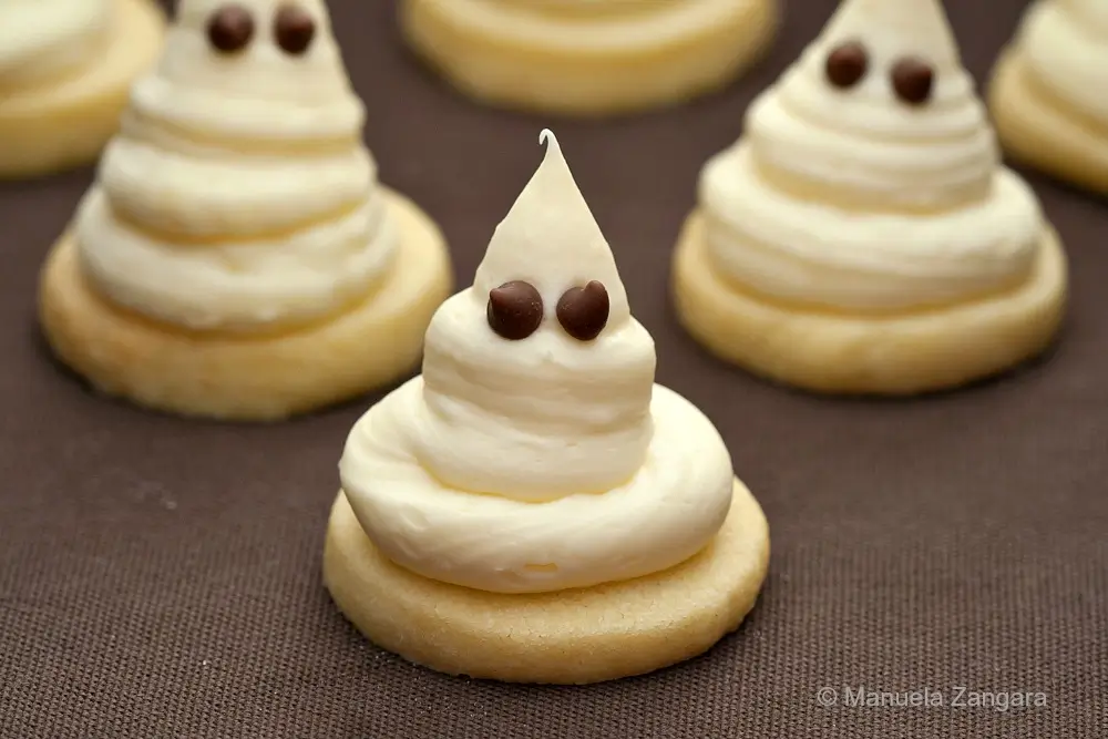 Halloween ghost cookies on shortbread bases arranged in rows.