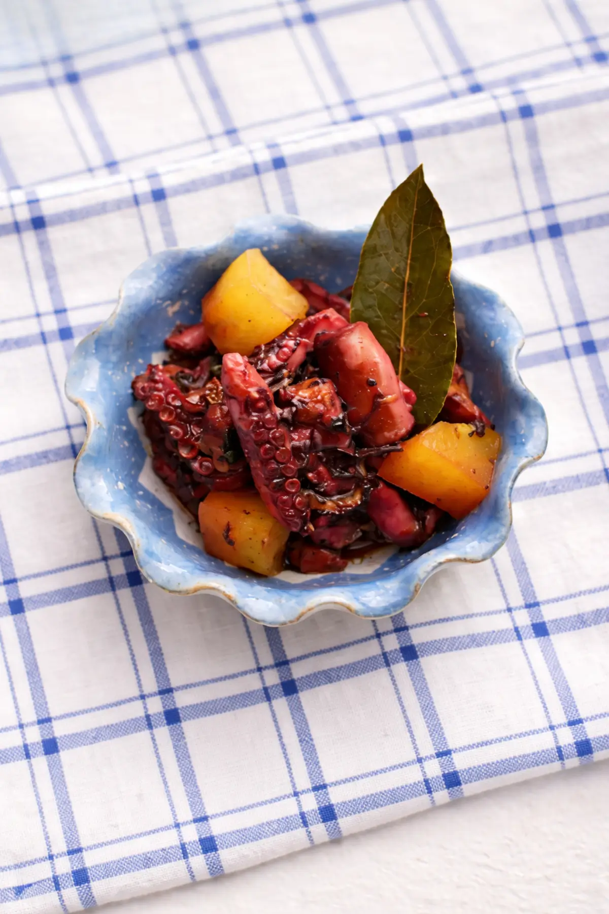 Close-up of tender octopus pieces with potatoes in a rich tomato sauce.