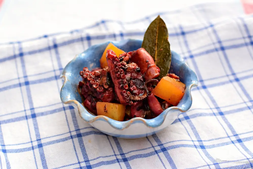 Polipo accupatello served in a small bowl with tender octopus, potatoes, and a bay leaf garnish.