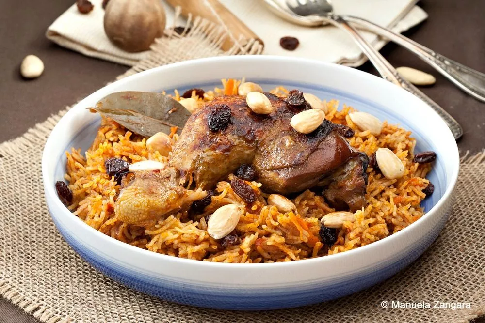 Saudi Chicken Kabsa with spiced rice, garnished with almonds and raisins.