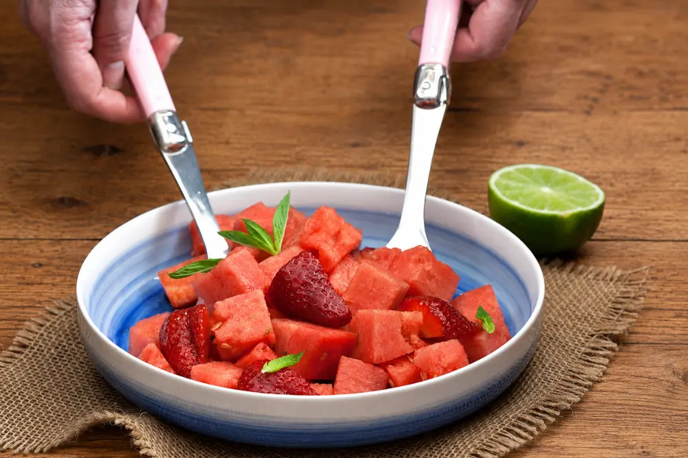 Fresh strawberry and watermelon salad garnished with mint leaves and served with a lime half.
