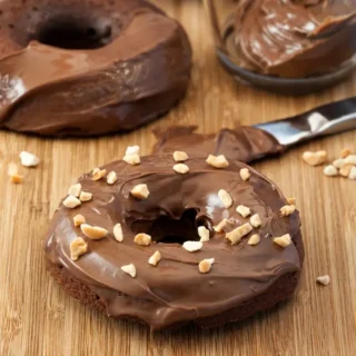 Glazed mini Nutella doughnuts with chopped hazelnuts and extra chocolate spread.