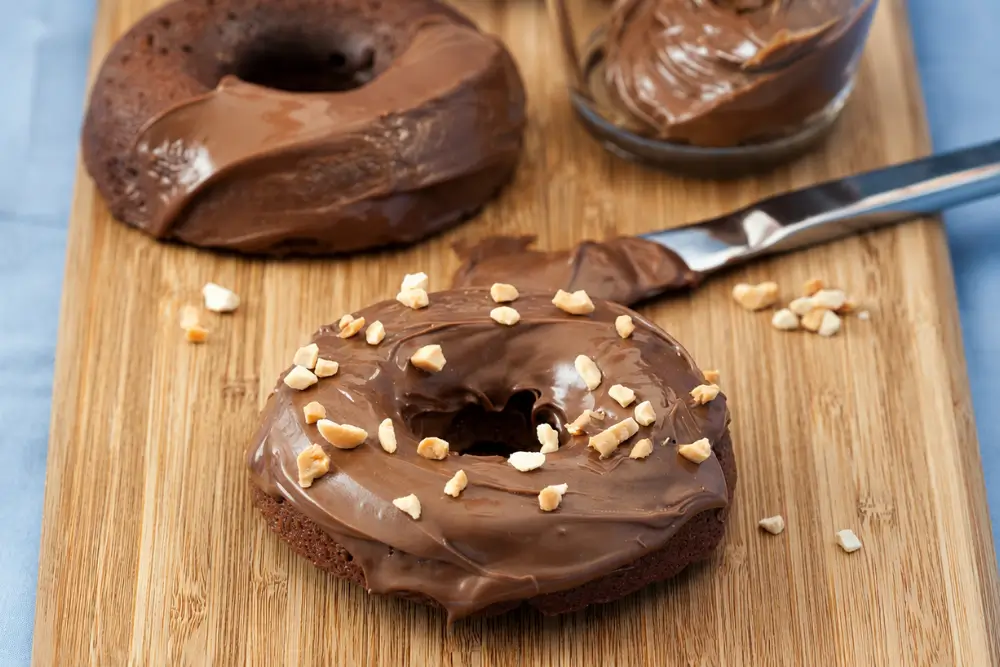 Glazed mini Nutella doughnuts with chopped hazelnuts and extra chocolate spread.