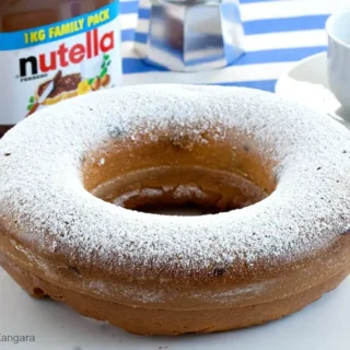 Whole ciambellone dusted with icing sugar on a plate.