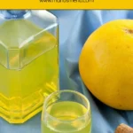 Bottle and glass of grapefruit liqueur arranged on blue cloth with a grapefruit.