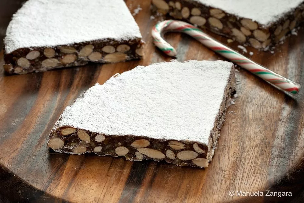 Close-up of authentic Panforte di Siena showing almonds and powdered sugar.