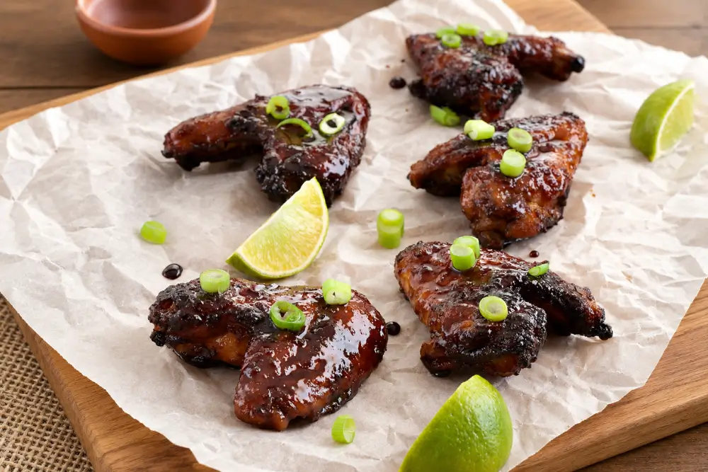 Glazed chicken wings served with sliced spring onions and fresh lime.