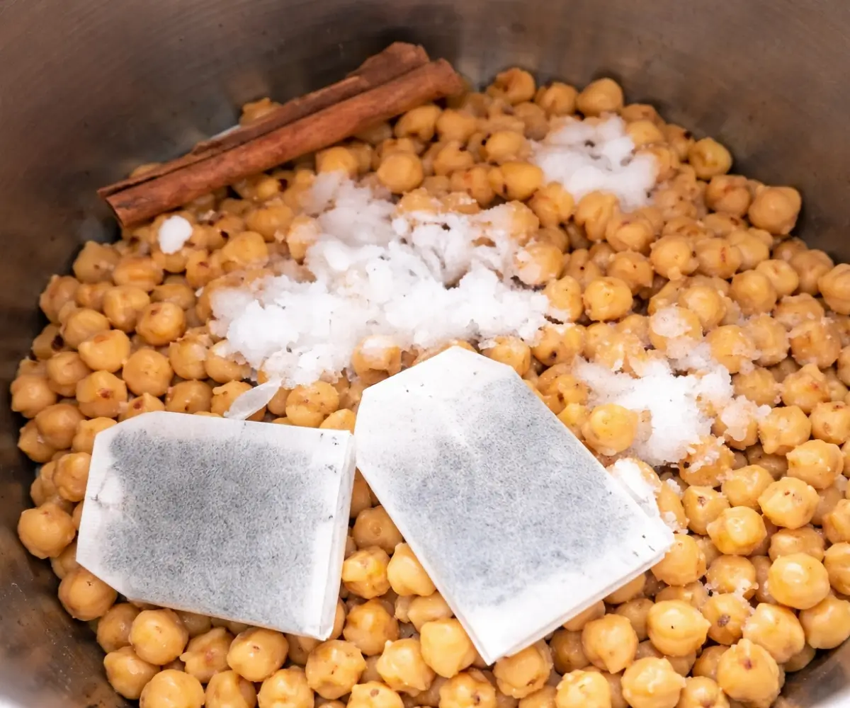 Chickpeas cooking with tea bags and whole spices in a pressure cooker.