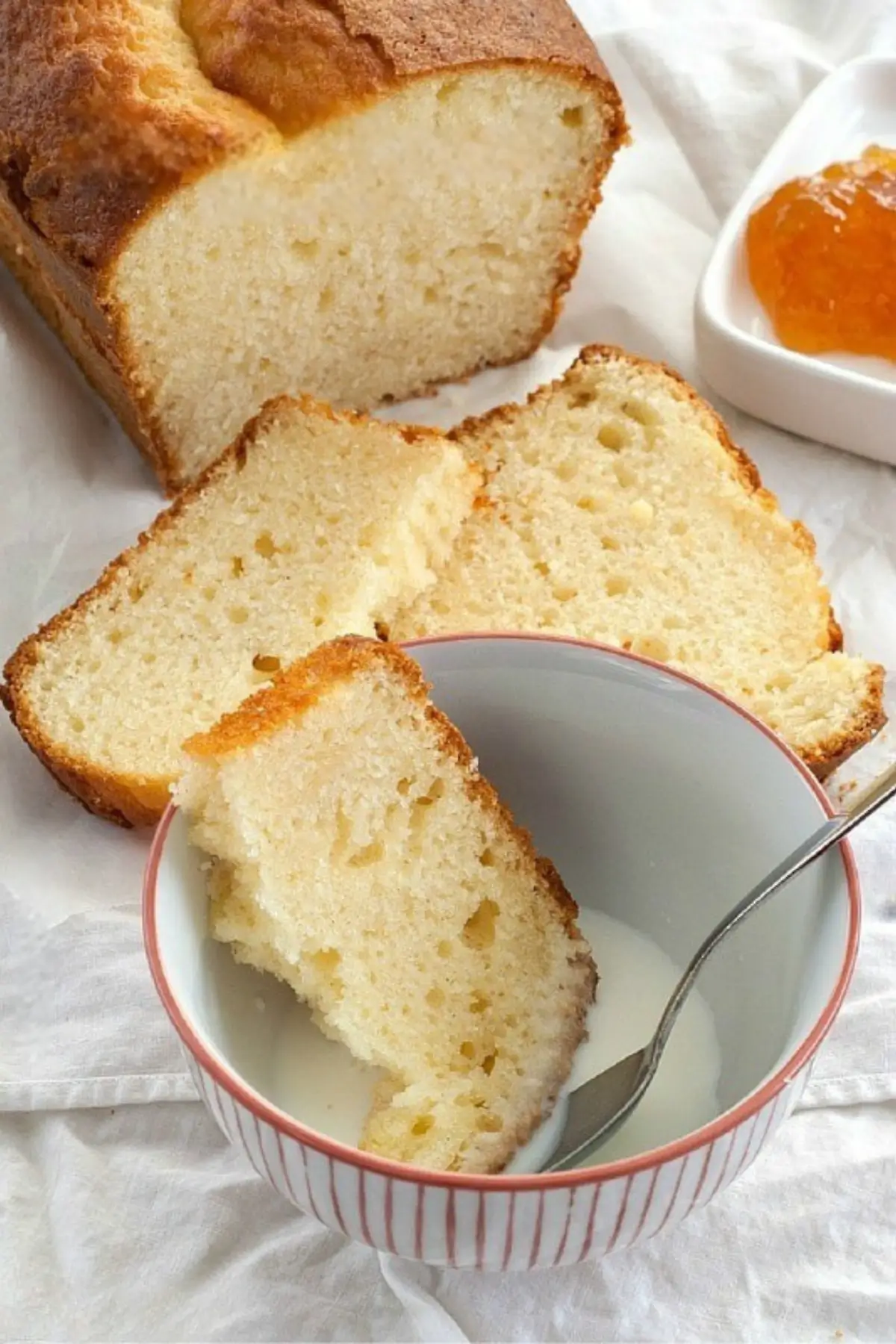 Slice of yogurt plumcake dipped into a bowl of milk.