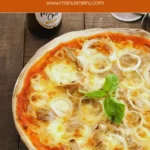 Close-up of a baked tuna and onion pizza with melted cheese and basil.