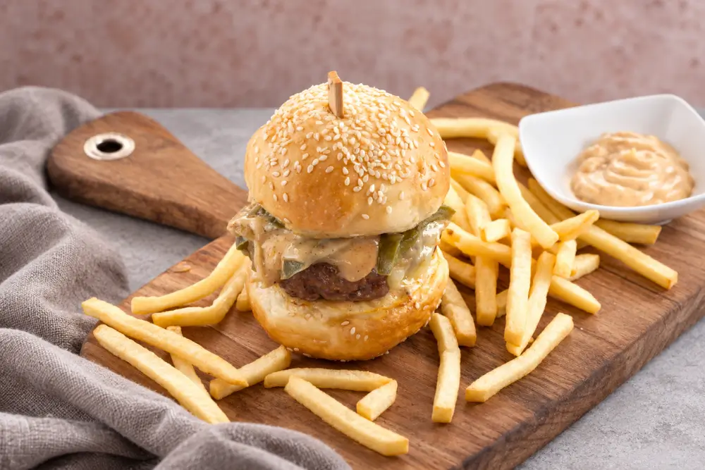 Cajun burger assembled with creamy mayo, melted cheese and vegetables.