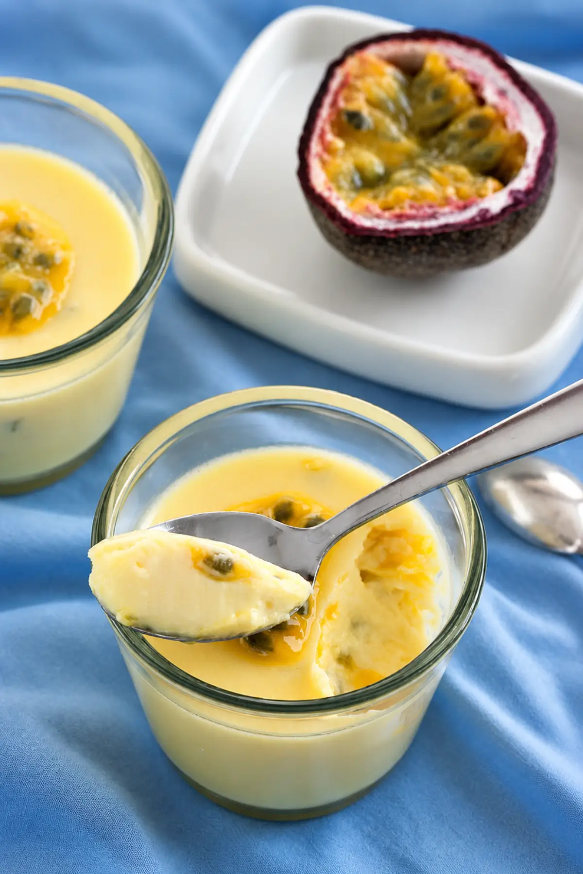Silky chilled posset with passion fruit topping and a spoonful showing the texture.