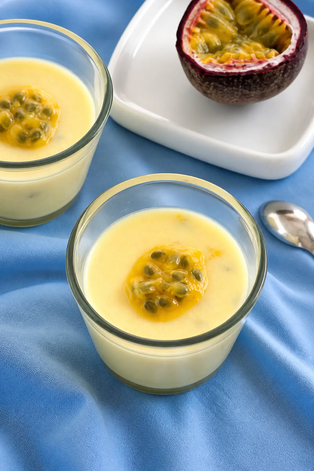 Creamy chilled dessert in glass ramekins topped with fresh passion fruit pulp.
