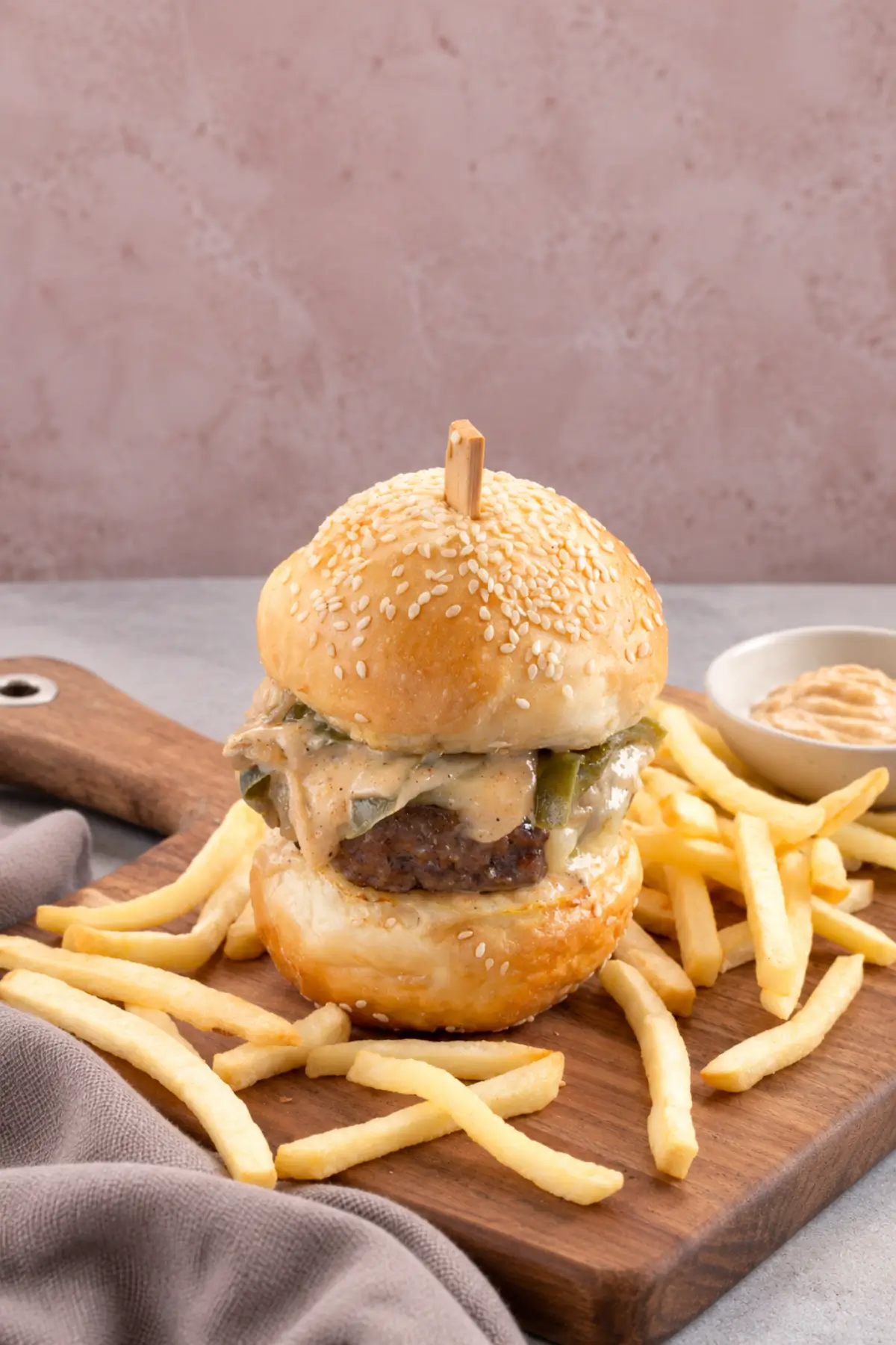 Homemade beef burger with melted cheese, cooked vegetables and fries.