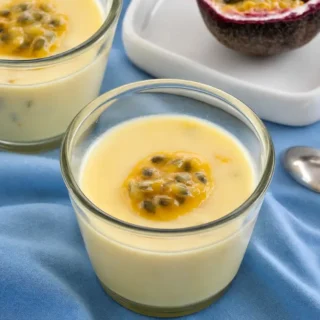 Passion Fruit Possets served in small glasses with fresh passion fruit on top.