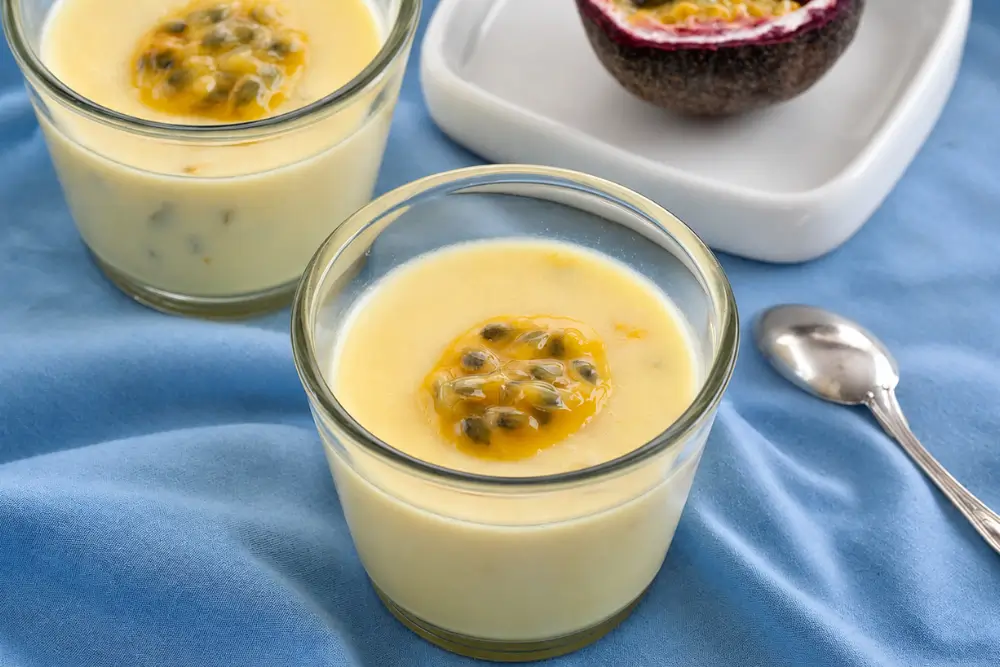 Passion Fruit Possets served in small glasses with fresh passion fruit on top.
