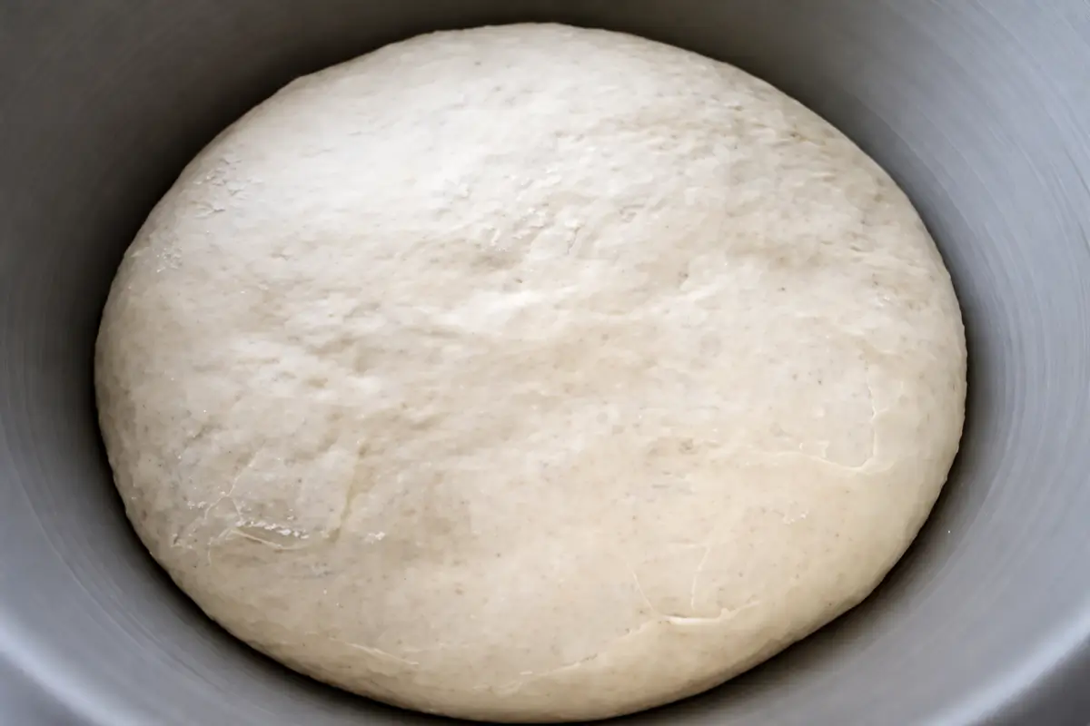 Soft, risen pizza dough resting in a bowl.