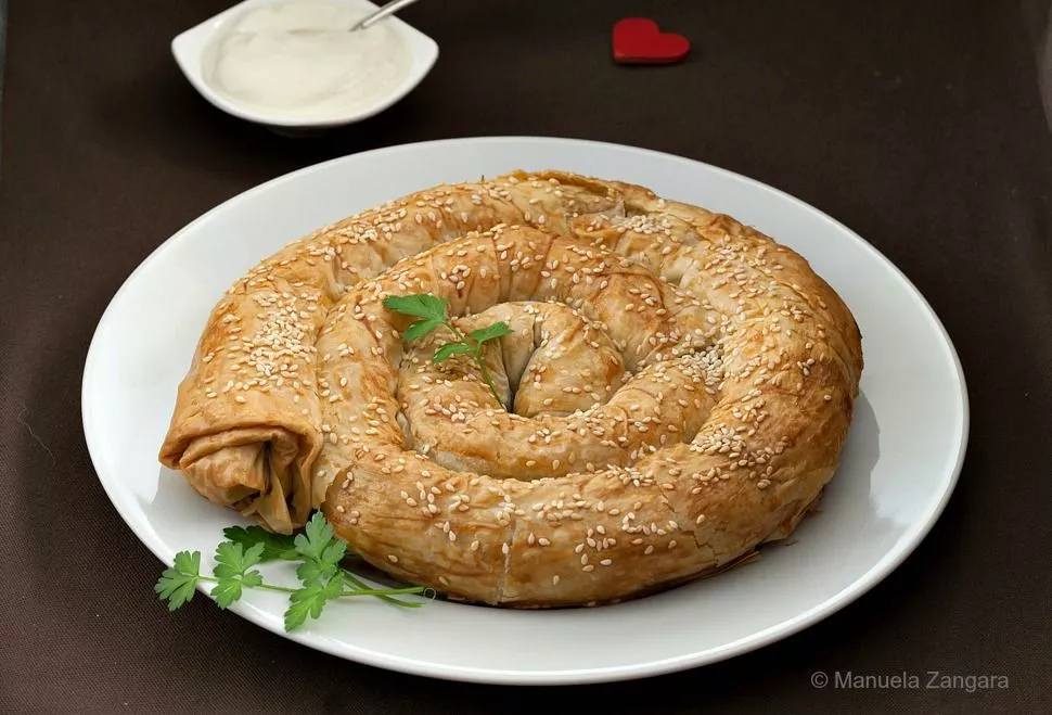 Traditional Bosnian burek spiral baked until golden and sprinkled with sesame seeds.