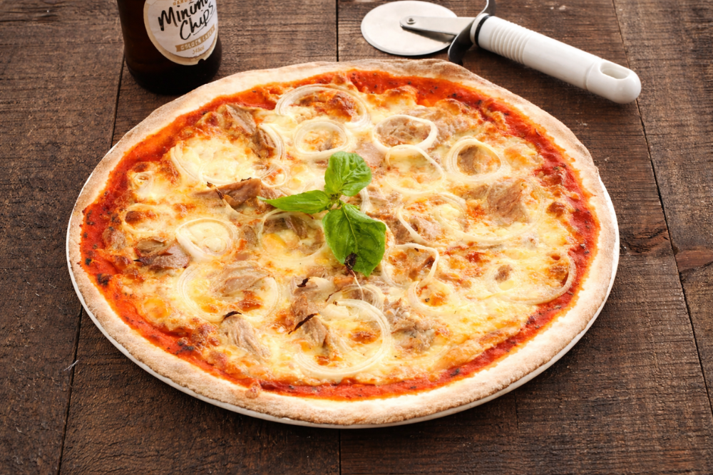 Freshly baked tuna and onion pizza with melted mozzarella, tender tuna pieces, and soft onion rings topped with basil.