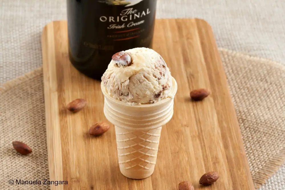 Scoop of Baileys Chocolate and Salted Almond Ice Cream in a waffle cone with roasted almonds on top.