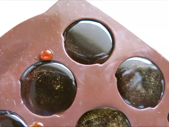 Dark caramel poured into a silicone mould to set into glossy discs.