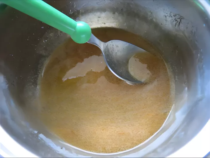 Caramel mixture cooking to the hard-crack stage with thermometer temperature shown.