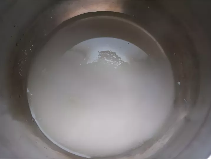 Sugar syrup beginning to dissolve and melt in a metal saucepan.