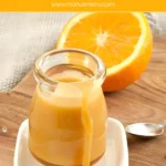 Orange caramel sauce dripping down a small glass jar on a white dish.