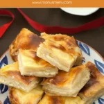 A plate full of sweet yoghurt burek pieces with crisp, golden tops.