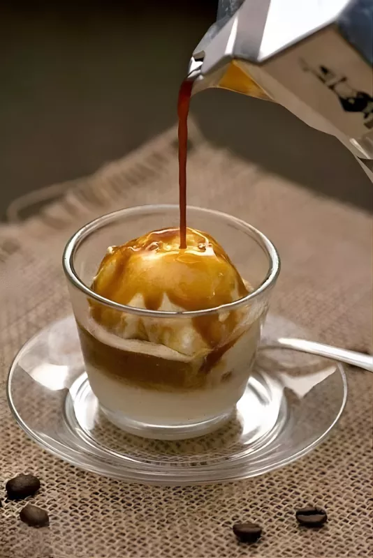 Pouring espresso over gelato in a glass cup to prepare Affogato al Caffè at home.