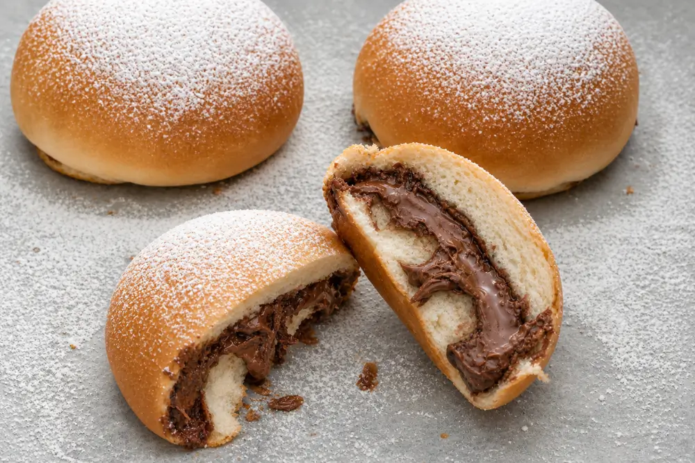 Golden baked buns filled with melted chocolate hazelnut spread and dusted with icing sugar.