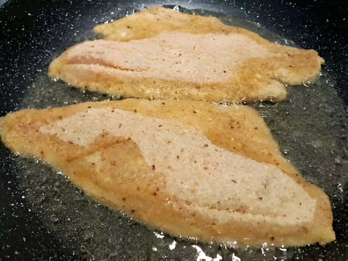 Barramundi fillets cooking in a pan.