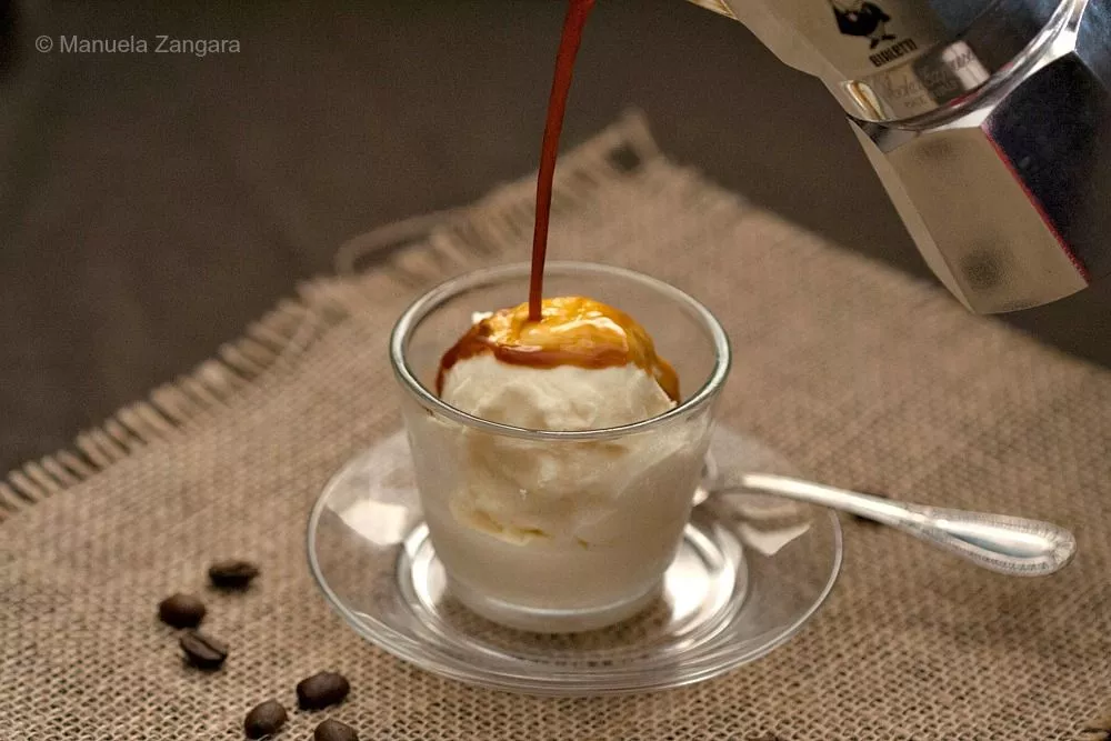 Freshly brewed espresso poured over vanilla gelato in a glass cup.