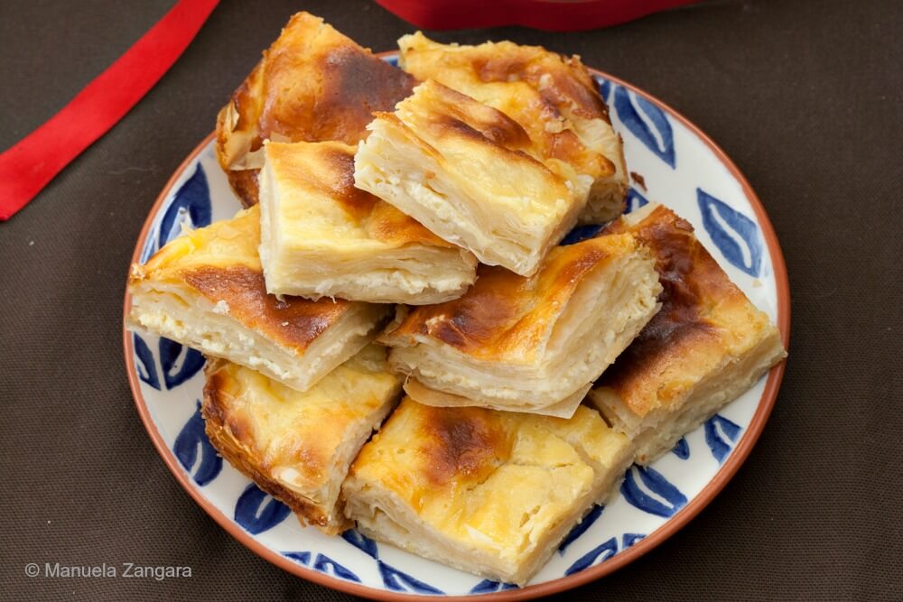 A plate full of sweet yoghurt burek pieces with crisp, golden tops.