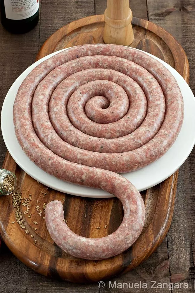 Homemade Sicilian pork sausage with fennel coiled on a plate.